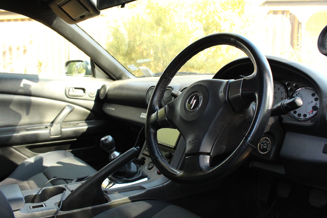 A messy JDM S15 interior, note the badge on the steering wheel
